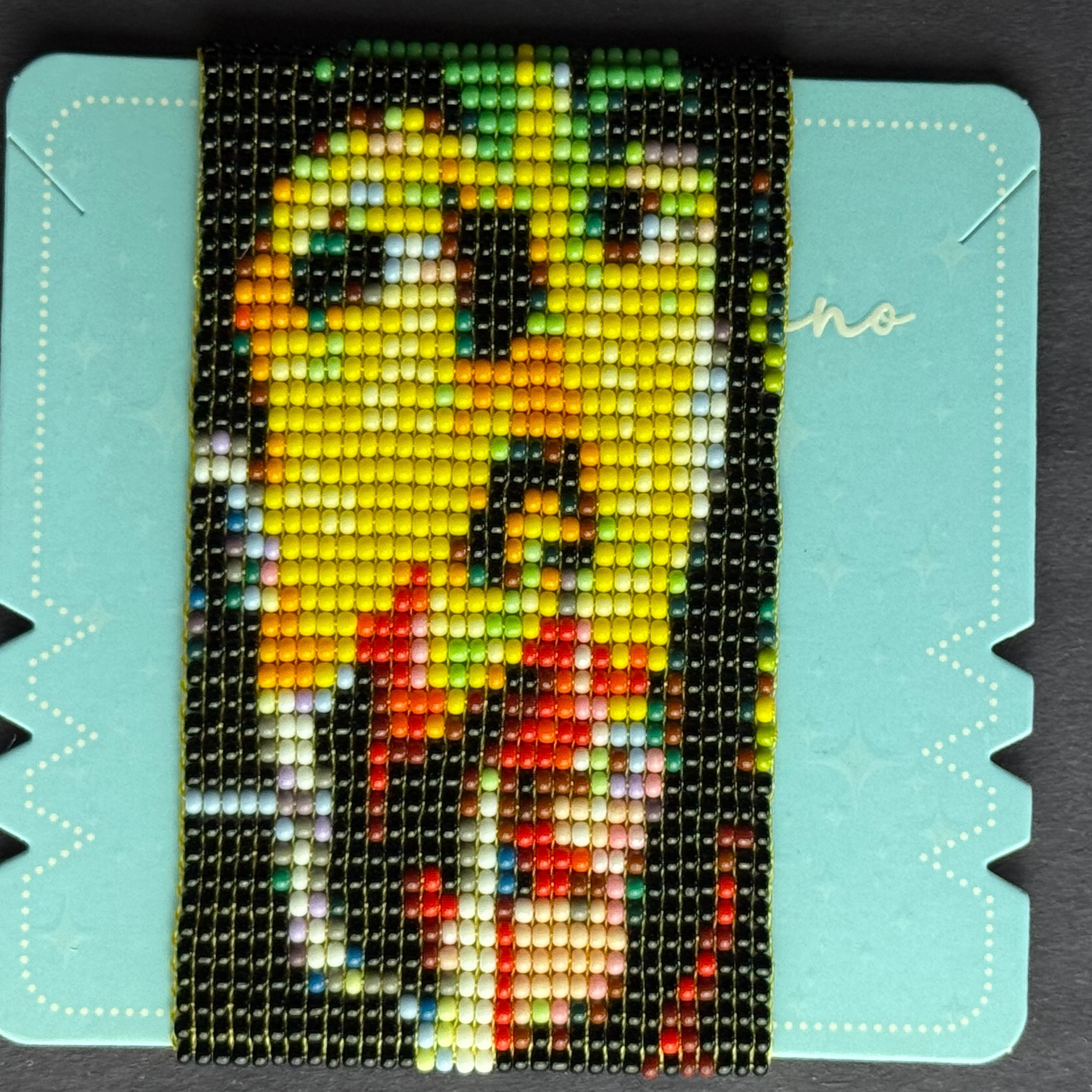 A beaded portrait of Bob Marley displayed on a light blue diamond painting canvas against a dark gray background.